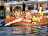 Dos niños disfrutan de la piscina en verano
