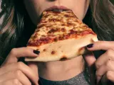 Imagen de archivo de una chica comiendo pizza.