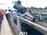 El coche accidentado ha acabado colgando de un puente.
