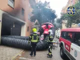 Bomberos trabajando en la extinción de un incendio en el aparcamiento de un edificio de viviendas en Pino Montano.
