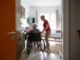 Una anciana en silla de ruedas junto a su cuidadora.