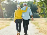Una pareja de jubilados camina al aire libre.