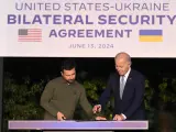 El presidente estadounidense Joe Biden (dcha.) y el presidente ucraniano Volodymyr Zelensky (izq.) firman un acuerdo de seguridad tras una reunión bilateral al margen de la cumbre del G7 en Savelletri (Brindisi), Italia, el 13 de junio de 2024.