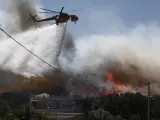 Un helicóptero tira agua para apagar el incendio de Atenas.
