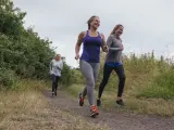 Tres mujeres corriendo por el campo.