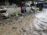 Los residentes se sientan en sus casas a lo largo de una carretera inundada por un deslizamiento de tierra causado por las fuertes lluvias en Baños, Ecuador, el lunes 17 de junio de 2024.