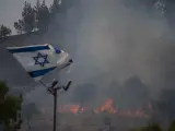 Una bandera israelí junto a un incedio provocado por el lanzamiento de cohetes de Hizbulá desde Líbano.