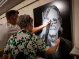 Dos personas tocan el retrato en relieve de Luis Eduardo Aute, realizado por el fotógrafo Juan Torre
