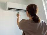 Una mujer regula el aire acondicionado en su vivienda.