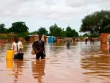 La gente lleva sus pertenencias mientras camina por una calle inundada por las aguas del río Níger que se desbordó en el barrio de Kirkissoye en Niamey el 27 de agosto de 2020.