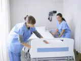 Dos enfermeras preparan una cama de hospital.