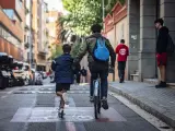 Dos niños se mueven en bici y patinete por Barcelona.