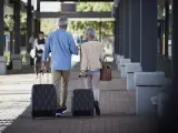 Dos personas con maletas caminan por la calle.