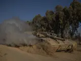 Soldados israelíes avanzan sobre un tanque cerca de la frontera entre Israel y Gaza.