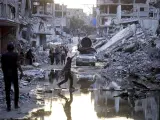 Palestinos desplazados caminan junto a las aguas residuales en la ciudad de Jan Yunis, en Gaza.