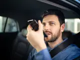 Hombre conduciendo con teléfono en la mano y cometiendo una infracción.