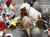 Varios mozos se caen mientras son perseguidos por los toros de la ganadería abulense de José Escolar Gil durante el séptimo encierro de los Sanfermines 2024.