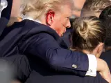 El expresidente Donald Trump, con la oreja ensangrentada, es ayudado a salir del escenario por agentes del Servicio Secreto tras sufrir un intento de asesinato.