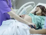 Una ginecóloga examina el vientre de mujer embarazada.
