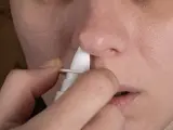 Una mujer aplicándose un spray nasal