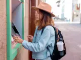 Una joven turista española sacando dinero de un cajero en el extranjero.