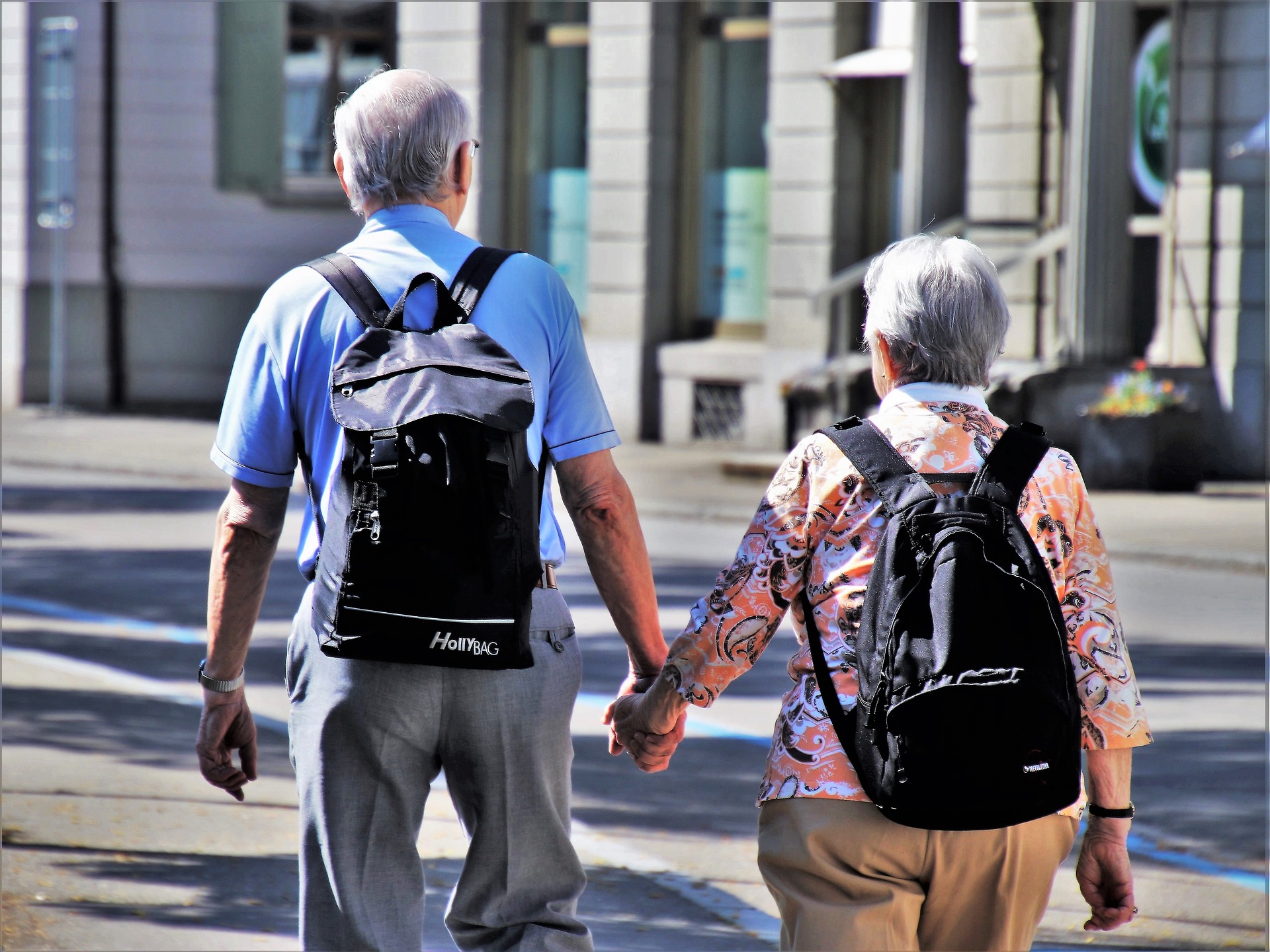Two elderly people walking with backpacks.